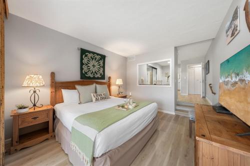 a bedroom with a large bed and a television at Kaanapali Royal H101 · KRL H101 Remodel 2BD Condo Pool Kaanapali in Kaanapali