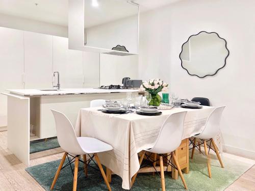 a white dining room with a table and chairs at Indulge Luxury Holiday Near Brighton Beach with Private Garden Parking in Melbourne