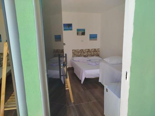 ein kleines Zimmer mit 2 Betten und einem Eingang in der Unterkunft Hospedagem da barra suites,praia barra grande,caminho de moises e antunes in Maragogi