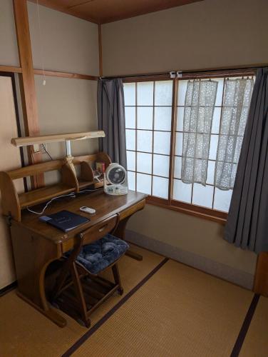 a room with a desk with a telephone and a window at private rooms in togo beach and park side house in Numazu