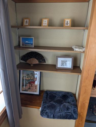 a room with wooden shelves with pictures and a blue ottoman at private rooms in togo beach and park side house in Numazu