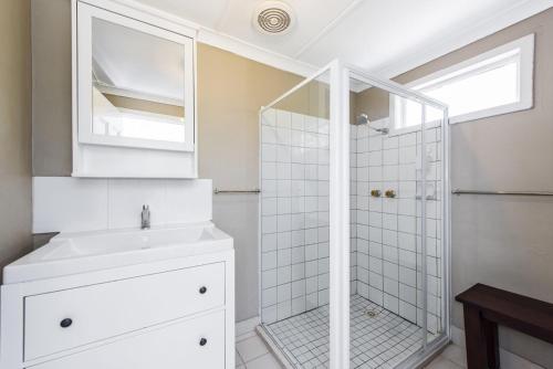 a white bathroom with a shower and a sink at Blueshack - Walking Distance To Foreshore in Guilderton