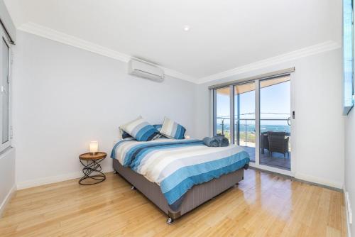 a bedroom with a bed and a large window at Ocean Sunset - Luxury Apartment with Ocean Views in Lancelin