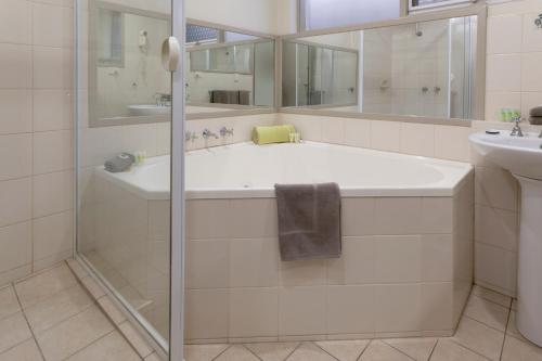 a white bathroom with a sink and a tub at Keilor Motor Inn in Keilor