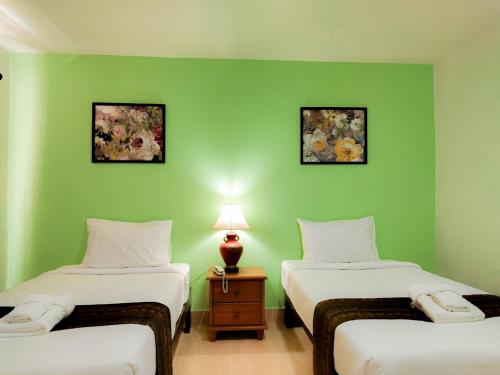two beds in a room with green walls at Angel Park Residence in Pattaya North