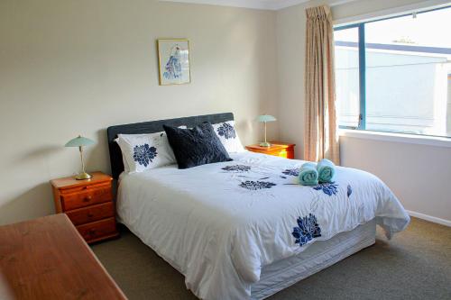 ein Schlafzimmer mit einem Bett und einem Fenster in der Unterkunft Monarch Cottage on the Estuary in Athenree