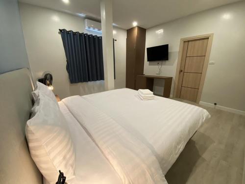 a bedroom with a large white bed and a television at The European Chiang Mai in Chiang Mai