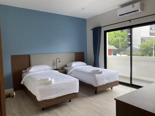 two beds in a room with a large window at The European Chiang Mai in Chiang Mai