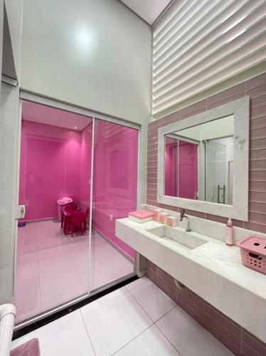 een roze badkamer met een wastafel en een spiegel bij Casa Linda, moderna e aconchegante in Rio Branco