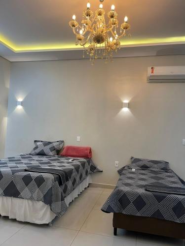 een slaapkamer met 2 bedden en een kroonluchter bij Casa Linda, moderna e aconchegante in Rio Branco