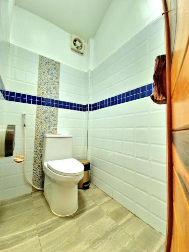a bathroom with a toilet and blue and white tiles at PIDA COFFEE FARM LODGE in Phumĭ Pu Pal