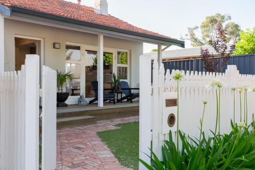 a white fence in front of a house at Guildford Cottage by Swan BnB Management in Perth