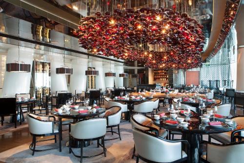 a restaurant with tables and chairs and a large chandelier at Four Seasons Hotel Guangzhou - Free Shuttle Bus to Canton Fair Complex & Overseas Buyer Registration Services during Canton Fair Period in Guangzhou