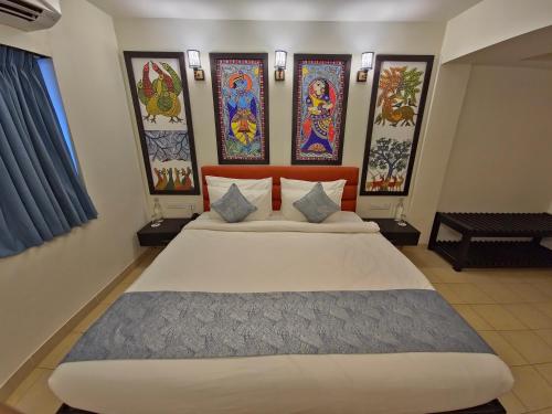 a bedroom with a large bed with paintings on the wall at Tathastu Tadoba in Mohurli