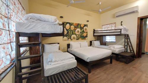 a room with three bunk beds and a room with a table at Tathastu Tadoba in Mohurli