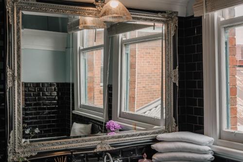 a mirror over a sink in a bathroom at La Cochon Rose Motel in Saint Arnaud