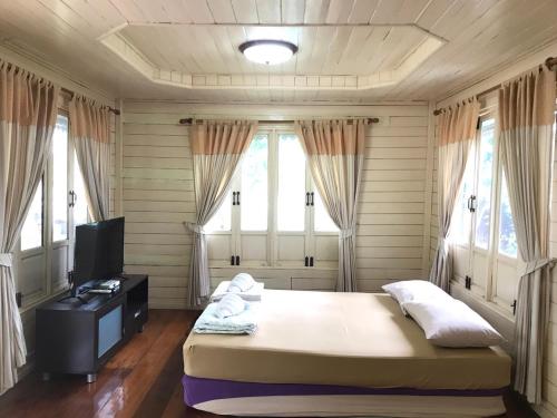 a bedroom with a bed and a tv and windows at Goldengold (Khaoyai) Resort & Spa in Mu Si
