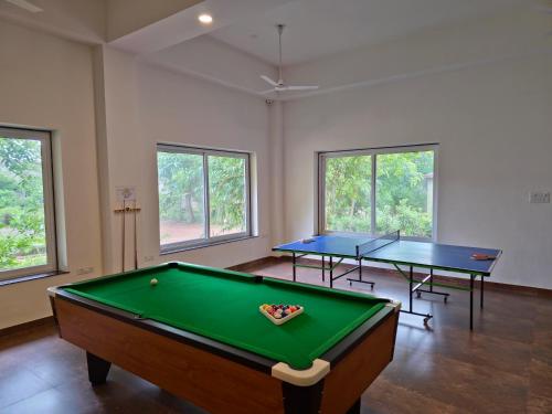 two ping pong tables in a room with windows at Tathastu Tadoba in Mohurli