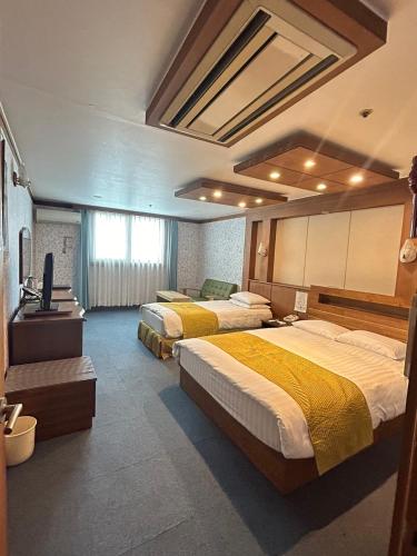 a hotel room with three beds and a television at Hotel Good Morning in Ulsan