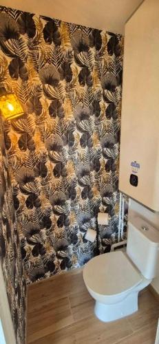 La salle de bains est pourvue de toilettes et d'un rideau noir et brun. dans l'établissement Escale Cabourgeaise, à Cabourg