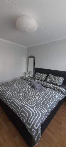 a bed with a black and white comforter and pillows at Istabiņa Carnikavā in Carnikava