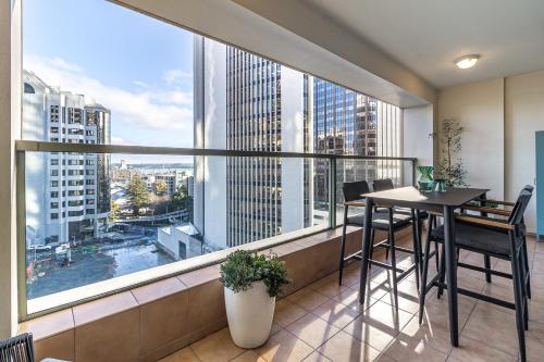 a balcony with a table and chairs and a large window at Luxurious Harbour View Apartment in Downtown in Auckland