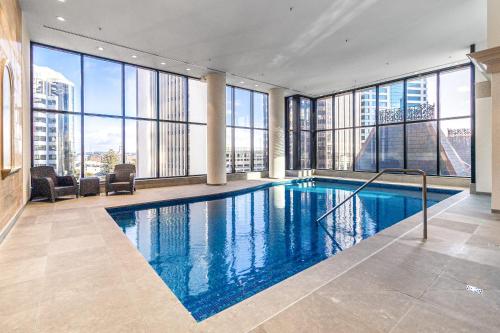 a large swimming pool in a building with windows at Luxurious Harbour View Apartment in Downtown in Auckland