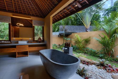 a bathroom with a bath tub and a sink at Samkhya Villas - Free 1x Floating Breakfast or Minibar in Ubud