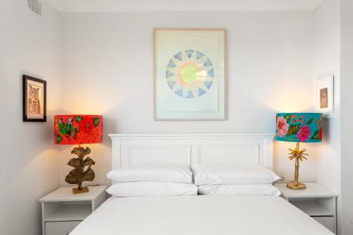 シドニーにあるPristine 2-Bed With Expansive Beach Viewsの白いベッドルーム(白いベッド1台、ランプ2つ付)