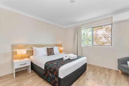 a white bedroom with a bed and a window at Castle Crest Motel in Townsville