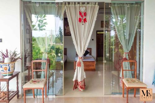 a room with glass doors and chairs and a bed at Emel's Retreat By Tropical Magnum - Luxury Boutique Villa in Anhandigoda