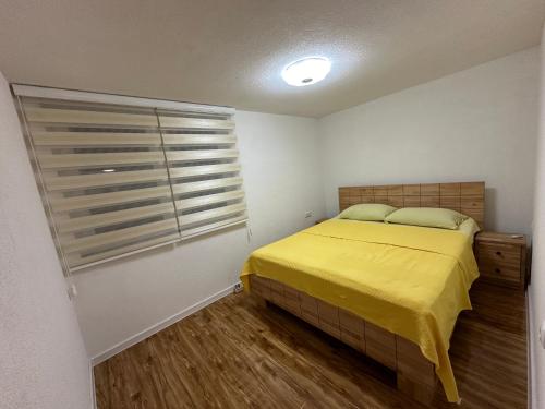 a bedroom with a yellow bed and a window at JB apartman Živinice in Živinice