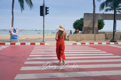 a woman in a red dress crossing a street at Luxury Edge Seaview Apartment in Pattaya Central