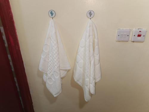 two white towels are hanging on a wall at Micasa Homes BNB in Kihingo