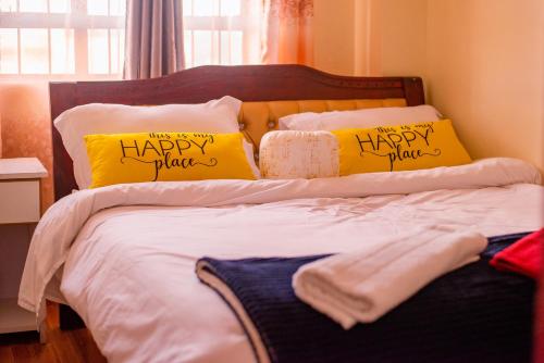 a bed with two yellow pillows with happy plans on it at Micasa Homes BNB in Kihingo