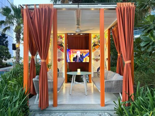 a patio with orange curtains and a table and a tv at Luxurious 2BDR Apartment in Paramount Towers with Burj Khalifa Views in Dubai