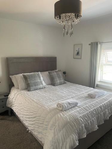 a bedroom with a bed with pillows and a chandelier at Woodbine Cottage-PART OF ALTON COTTAGES in Alton