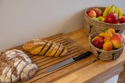 a wooden table with a basket of fruit and a knife at Délceg Réce Minihotel in Balatonkenese