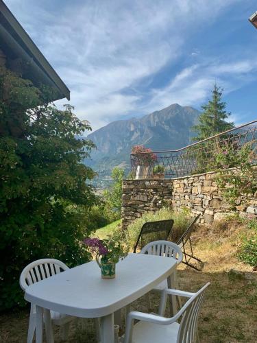 une table et des chaises blanches sur une terrasse avec des montagnes dans l'établissement Jourcins Jardin avec vue Montagne, à Saint-André-dʼEmbrun