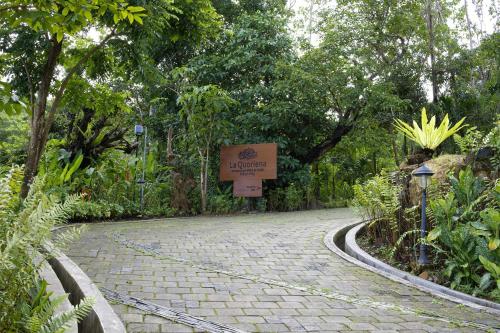 a cobblestone road in a garden with a sign at La Quoriena Botanical Villa & Cafe' in Labuan Bajo