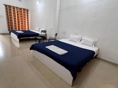 a bedroom with two beds with blue and white sheets at Mikunj Farms Karjat in Karjat