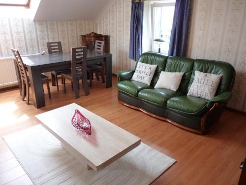 a living room with a green couch and a table at Gite les bons amis in Plombières