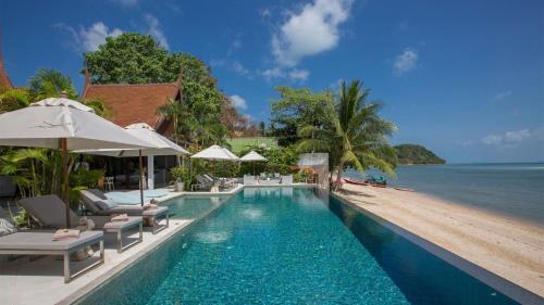 une piscine avec chaises et parasols au bord de l'océan dans l'établissement Chic Baan Capo - Luxury Four Bedroom Beachfront Villa, à Bangrak Beach