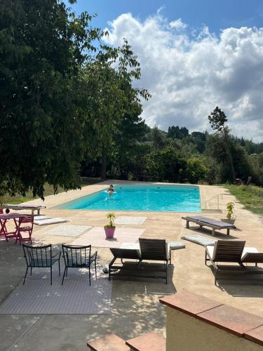 une piscine avec des chaises et des tables et une personne dans l'eau dans l'établissement 3 pièces au dernier étage dans bastide grassoise, à Grasse