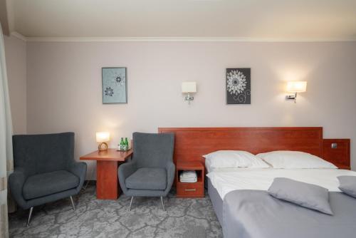 a bedroom with a bed and two chairs and a desk at Hotel Badura in Wadowice