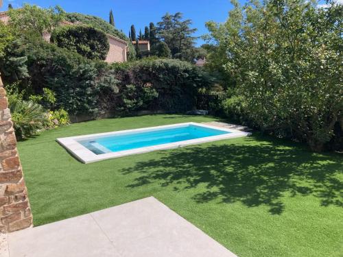 - une piscine dans une cour avec de l'herbe verte dans l'établissement La Cigalière à 5 minutes de la plage à pied, au Lavandou