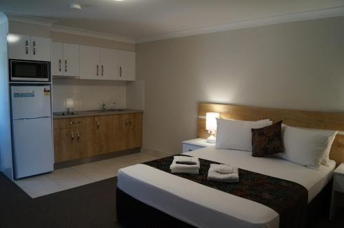 a hotel room with a bed and a kitchen at Castle Crest Motel in Townsville