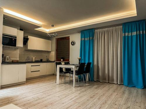 a kitchen with a table and some blue curtains at Apartament Lux Gdańsk Nowa Motława in Gdańsk