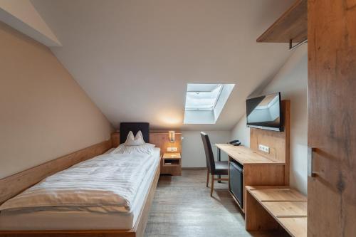 a bedroom with a bed and a desk and a television at Gasthof Gruber in Fridolfing
