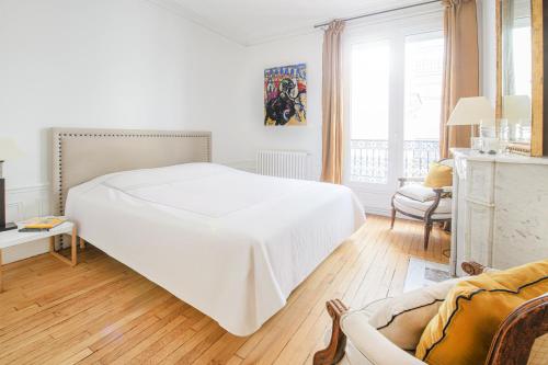 une chambre blanche avec un grand lit et une chaise dans l'établissement Appartement d'une chambre près de Montmartre, à Paris